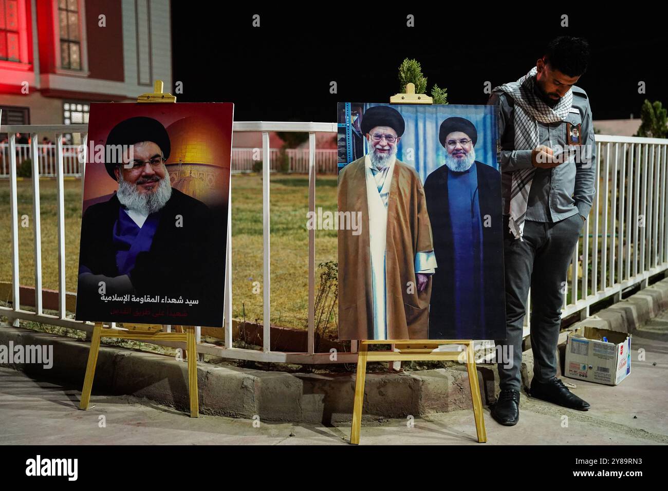 Bartella District, Nineveh, Iraq. 30th Sep, 2024. A man stands next to a banner with portraits of Iran's Supreme Leader Ayatollah Ali Khamenei (L), Hassan Nasrallah (R), during a memorial service for Hassan Nasrallah, the late leader of the Lebanese Shiite group Hezbollah who was killed in an Israeli airstrike in Beirut days ago, in Bartella district east of Mosul, northern Iraq. (Credit Image: © Ismael Adnan/SOPA Images via ZUMA Press Wire) EDITORIAL USAGE ONLY! Not for Commercial USAGE! Stock Photo