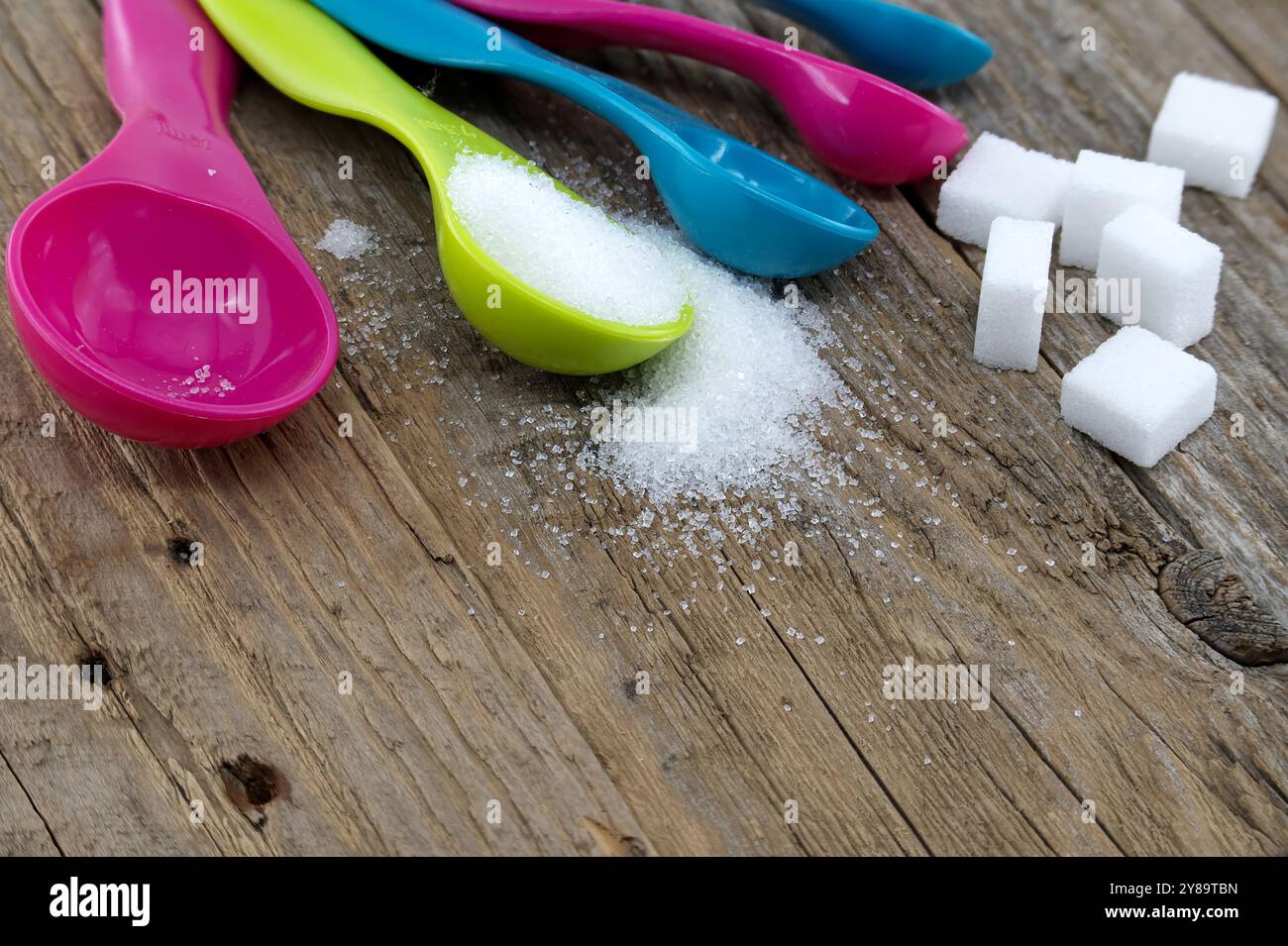 Array of sugar presentations on a wooden table, showcasing sugar cubes and granulated sugar Stock Photo