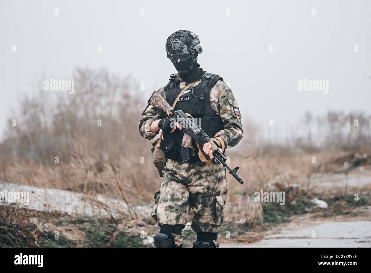 Soldier or militiaman in camouflage with assault rifle fighting in ruins. A special forces soldier in uniform walks against the background of a destro Stock Photo