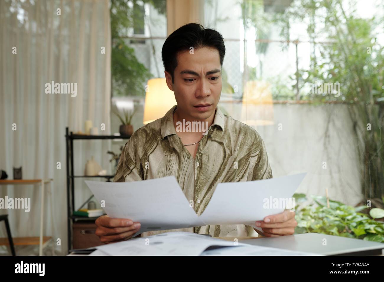 Man Examining Documents At Home Stock Photo
