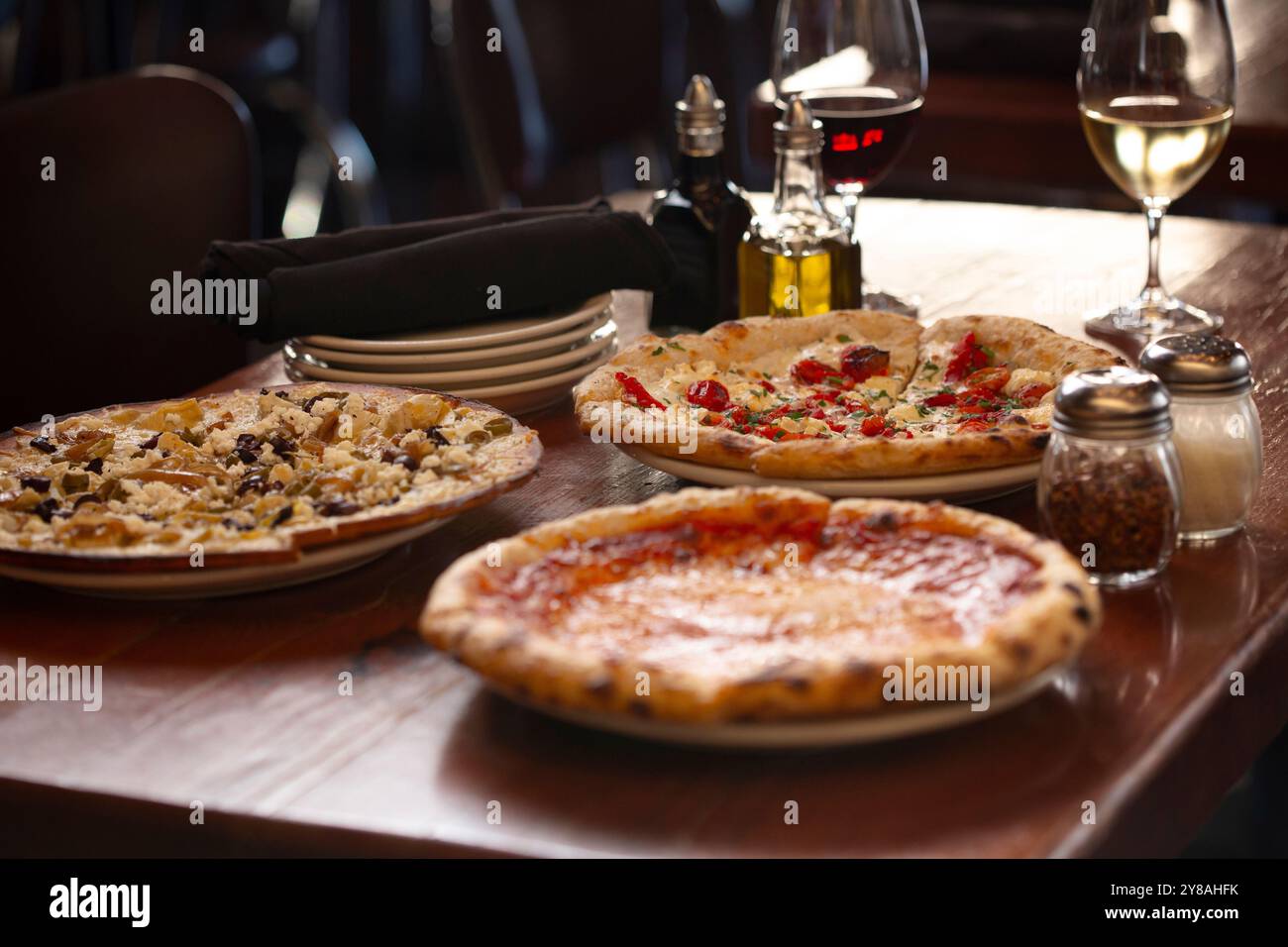A trio of pizzas and flatbreads on wood table Stock Photo