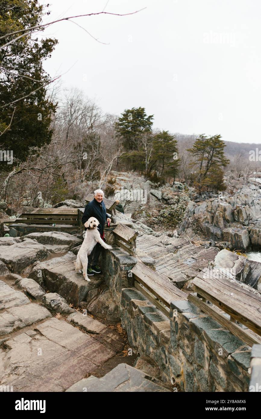 Older man hikes in mountain and rocks with tree and his pet dog Stock ...