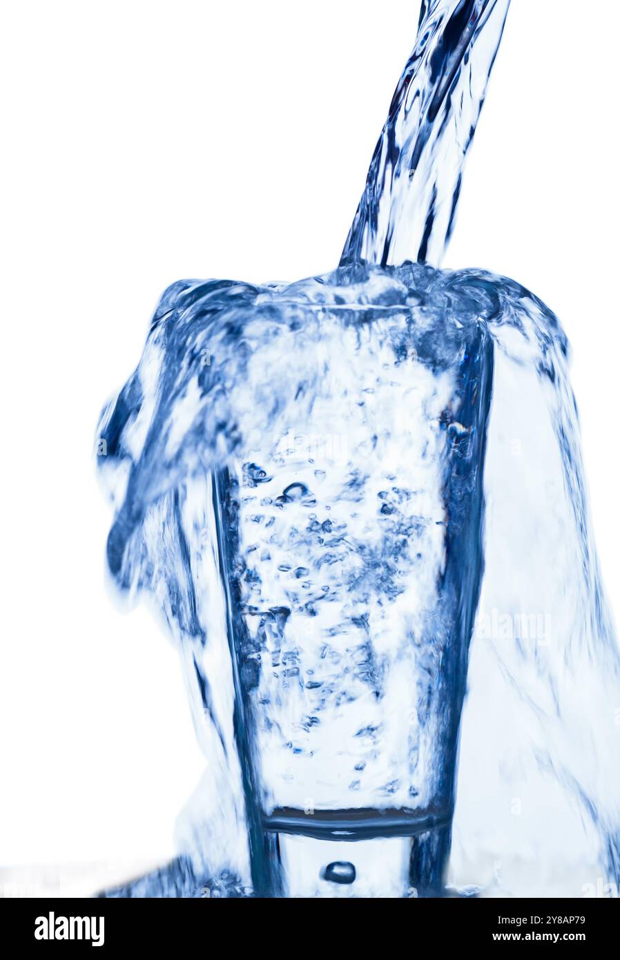 Water is poured into a glass and overflows, cut out Stock Photo