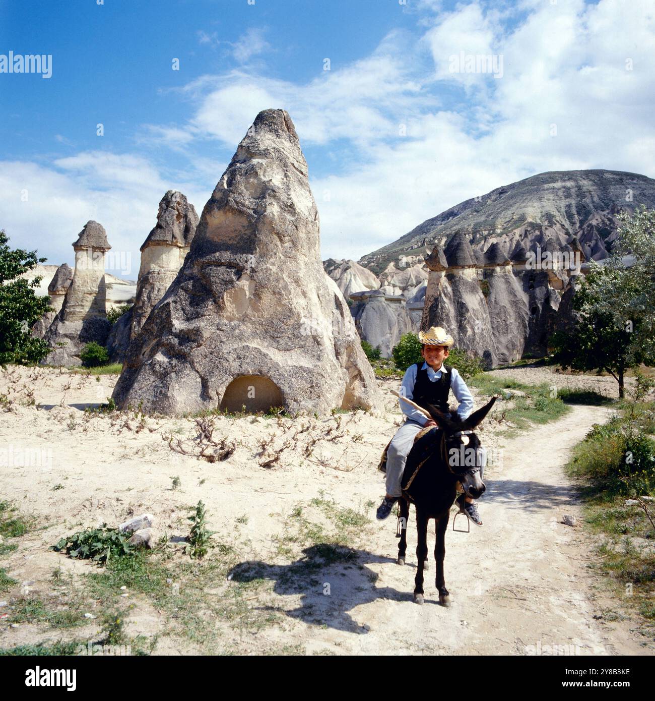 Ein Junge reitet auf einem Esel durch die typische Landschaft Kappadokiens mit ihren Erdpyramiden bei Göreme in der Provinz Nevsehir NevÅüehir, Türkei um 1988. 900200000710 Stock Photo