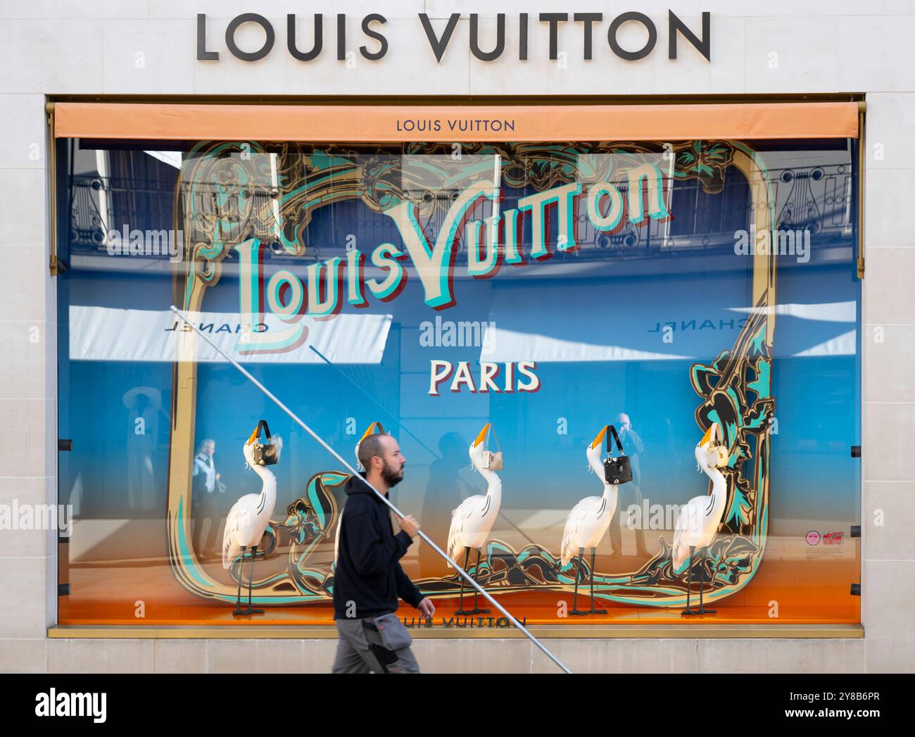 New Bond Street, London, UK. 4th Oct, 2024. Sunny morning in London's premier luxury shopping street after several days of drizzle and grey skies. Man with a long pole passes the Parisien styled window of Louis Vuitton. Credit: Malcolm Park/Alamy Live News Stock Photo