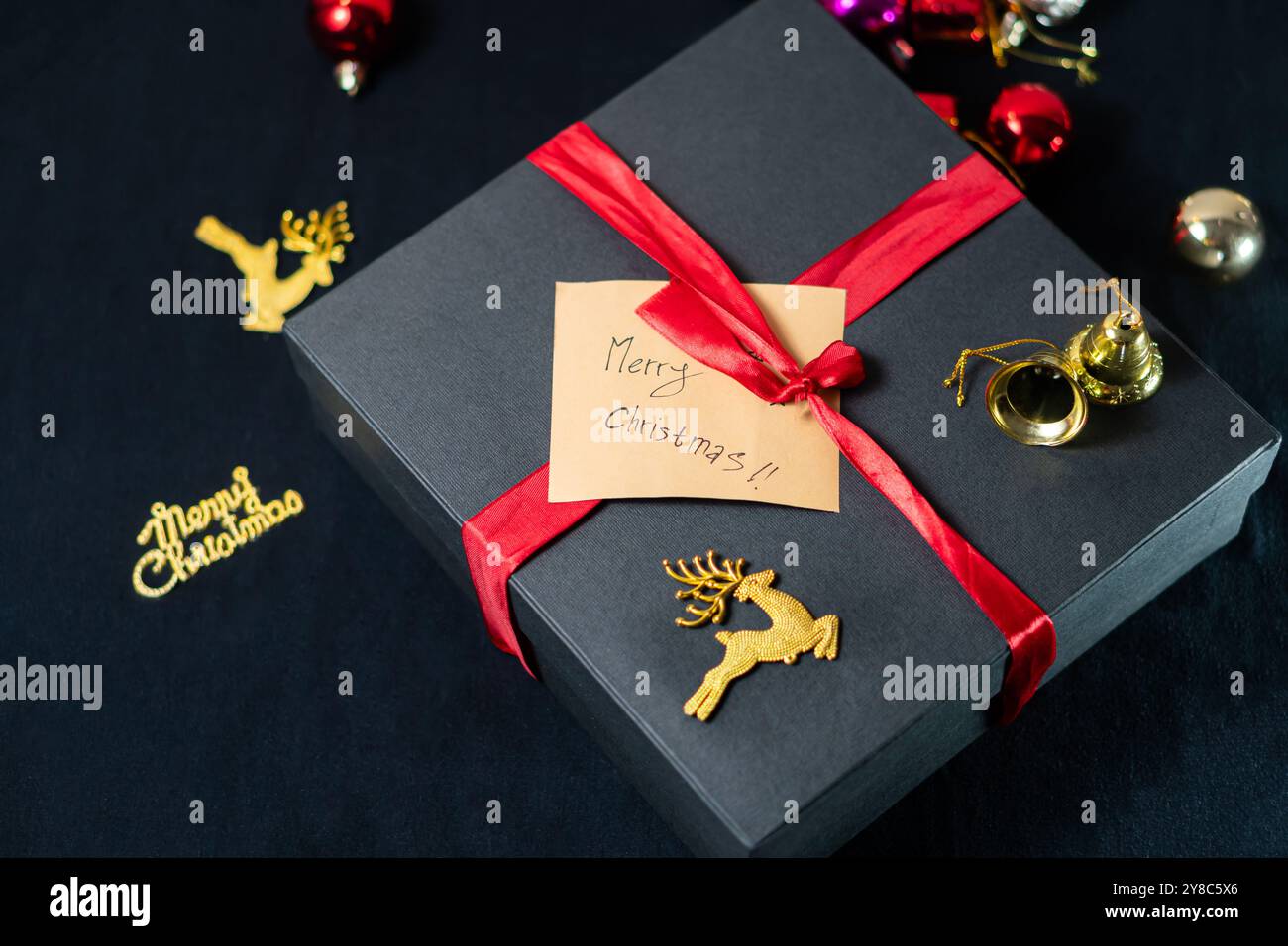 A beautifully wrapped Christmas gift in dark paper, adorned with a red ...