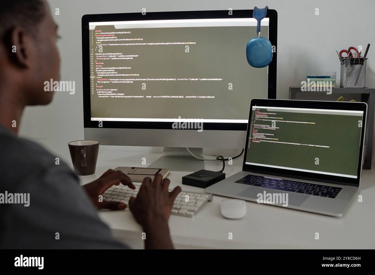 Unrecognizable talented programmer surrounded with electronic devices writing codes Stock Photo