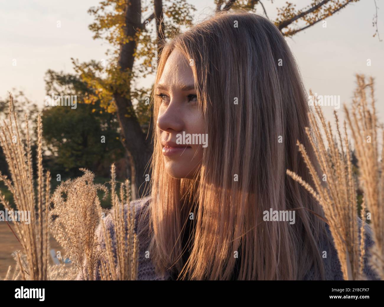 A woman with long, blonde hair stands in a field of tall grass, looking ...
