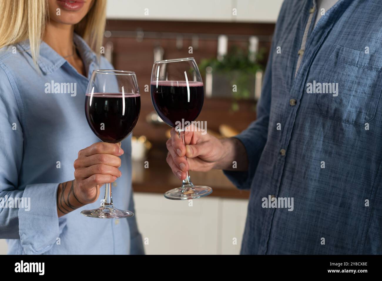 Happy couple having fun and toasting standing on a kitchen with red wine, Close-up Stock Photo