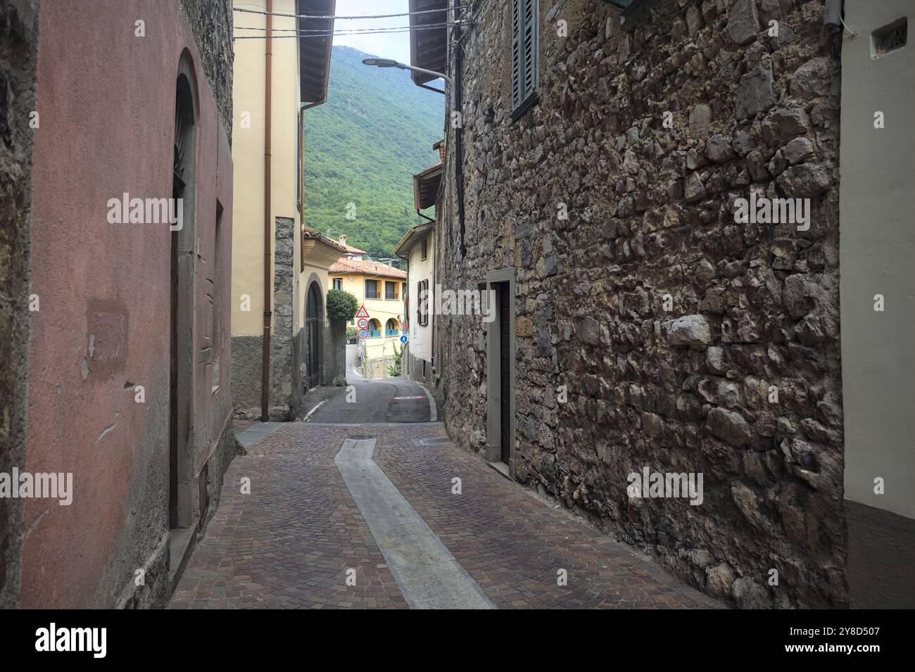 Narrow street bordered by houses in a town in the mountains on a cloudy day Stock Photo