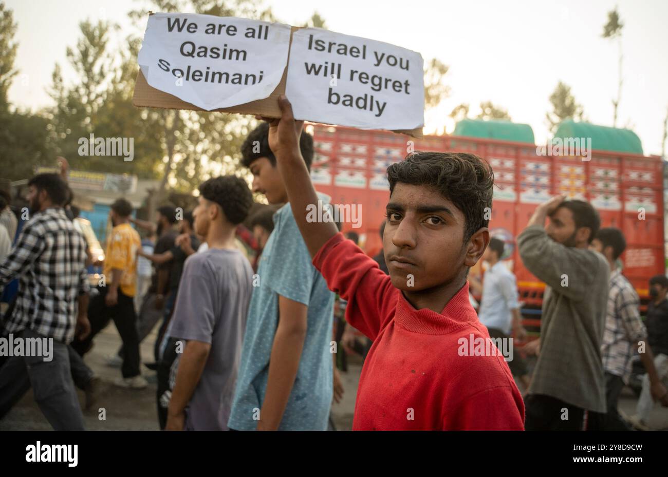 A Kashmiri Shia Muslim boy holds a placard that says "We are all Qasim ...