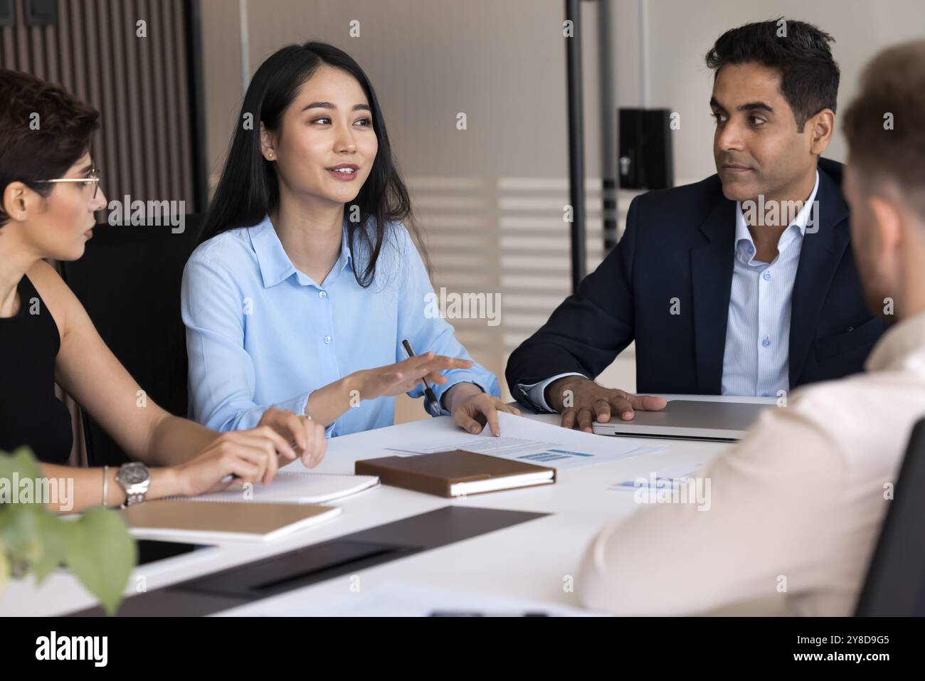Positive young Asian project manager presenting marketing strategy to colleagues Stock Photo