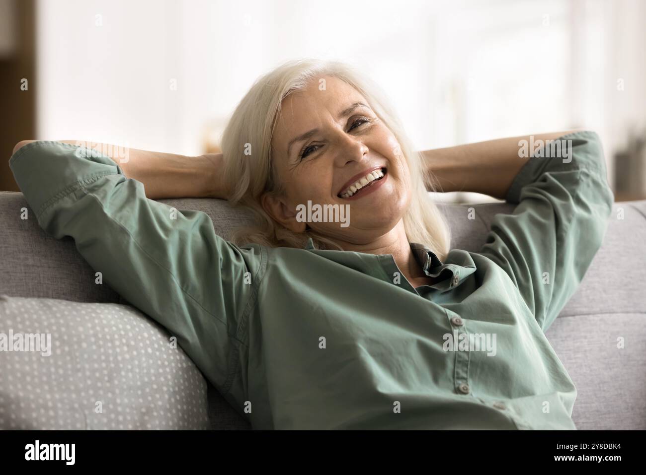 Carefree mature female leaned on sofa relaxing at home Stock Photo