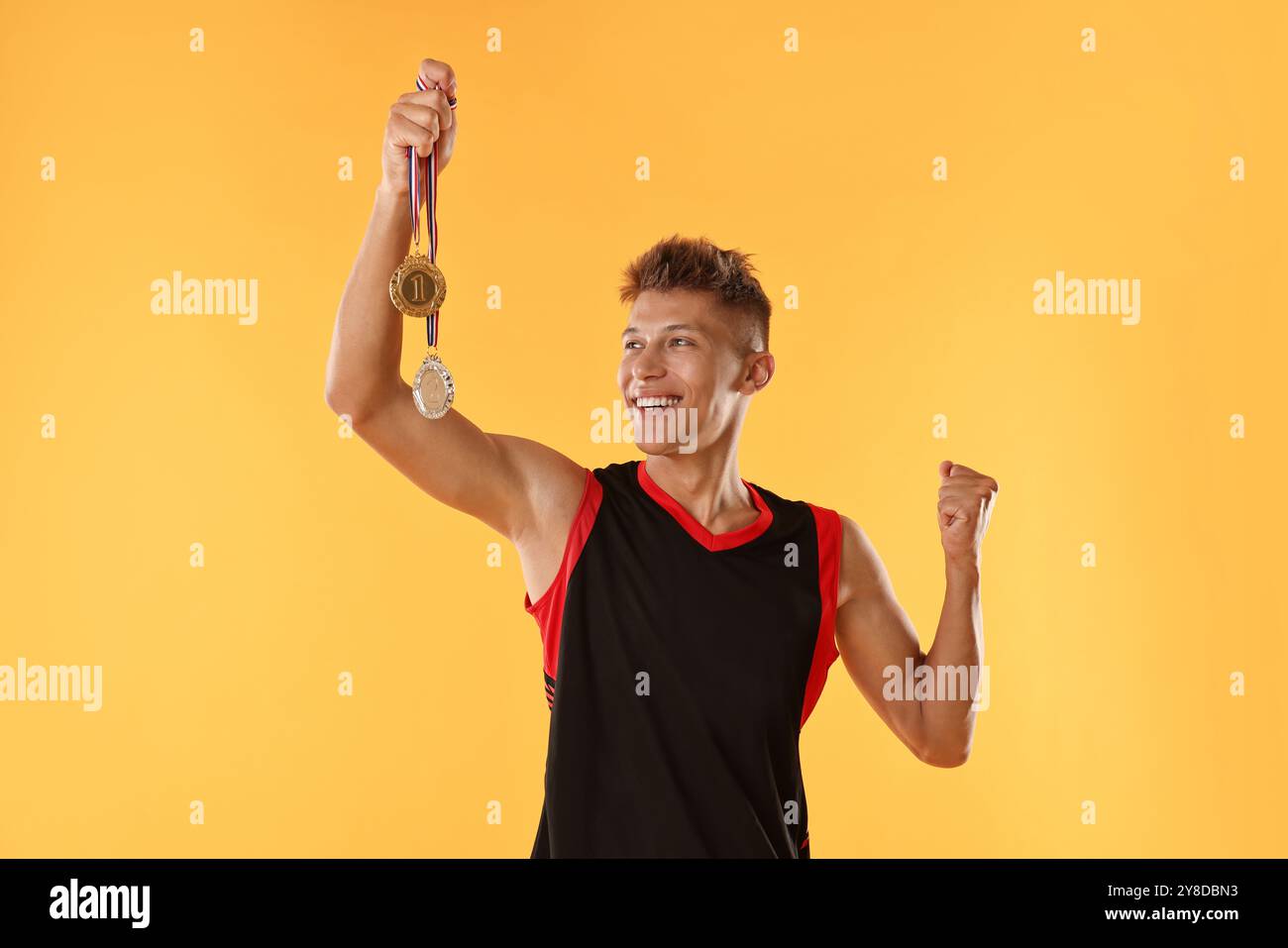 Happy winner with different medals on yellow background Stock Photo - Alamy