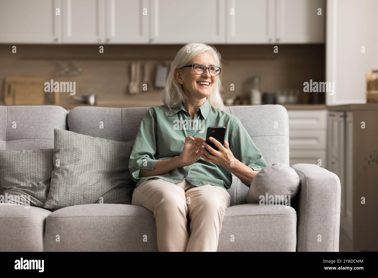 Happy smiling mature woman using smartphone at home Stock Photo