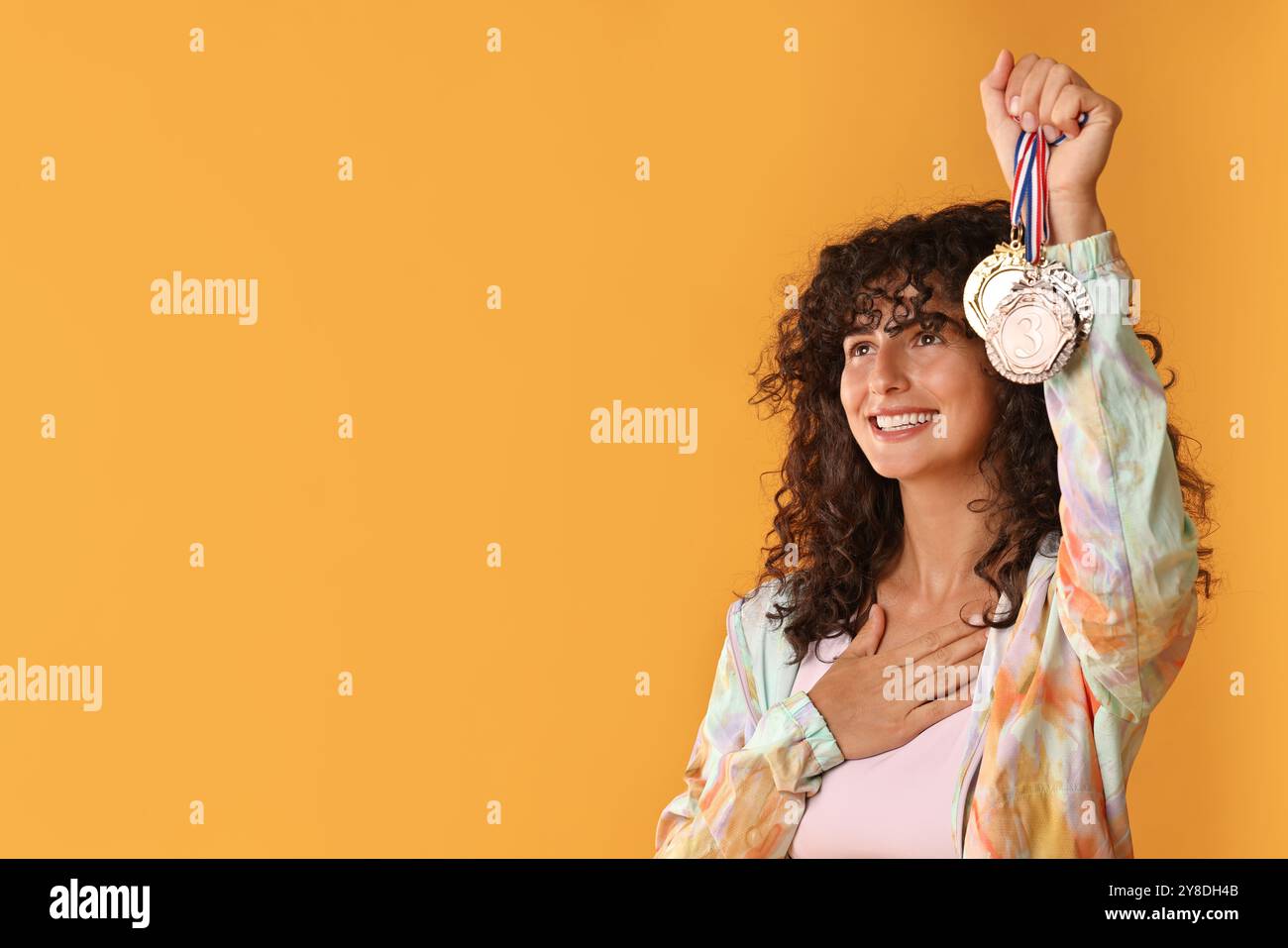 Happy winner showing different medals on yellow background. Space for ...