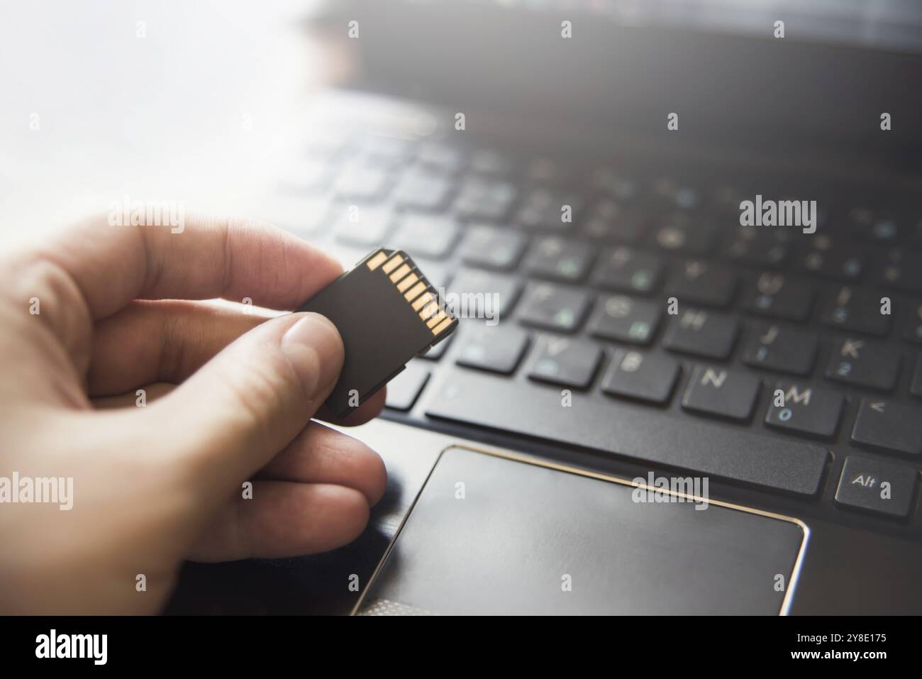 Memory card in hand, laptop, keyboard. flash drive information. data base Stock Photo