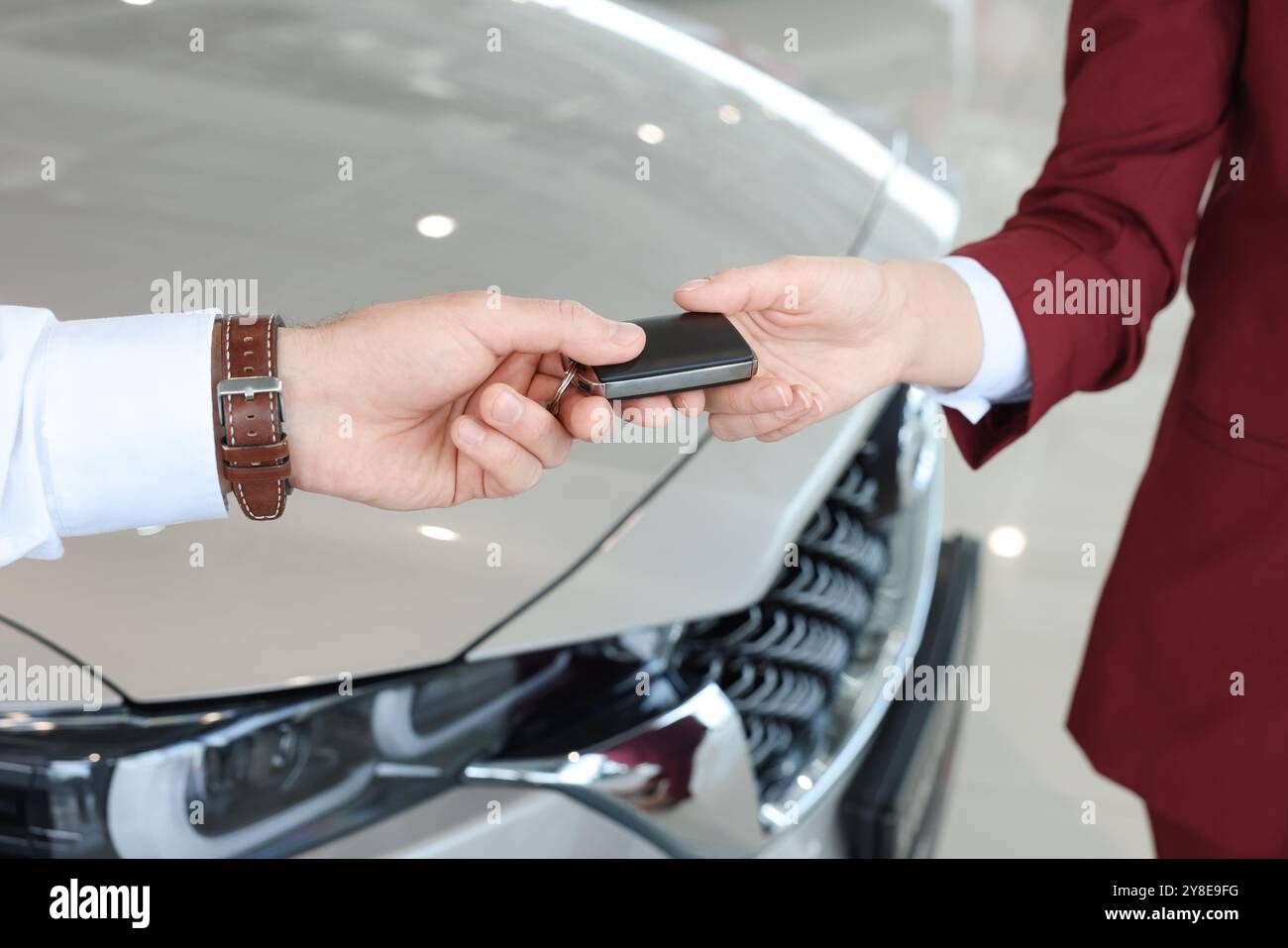 Salesman giving key to client near new car in salon, closeup Stock ...