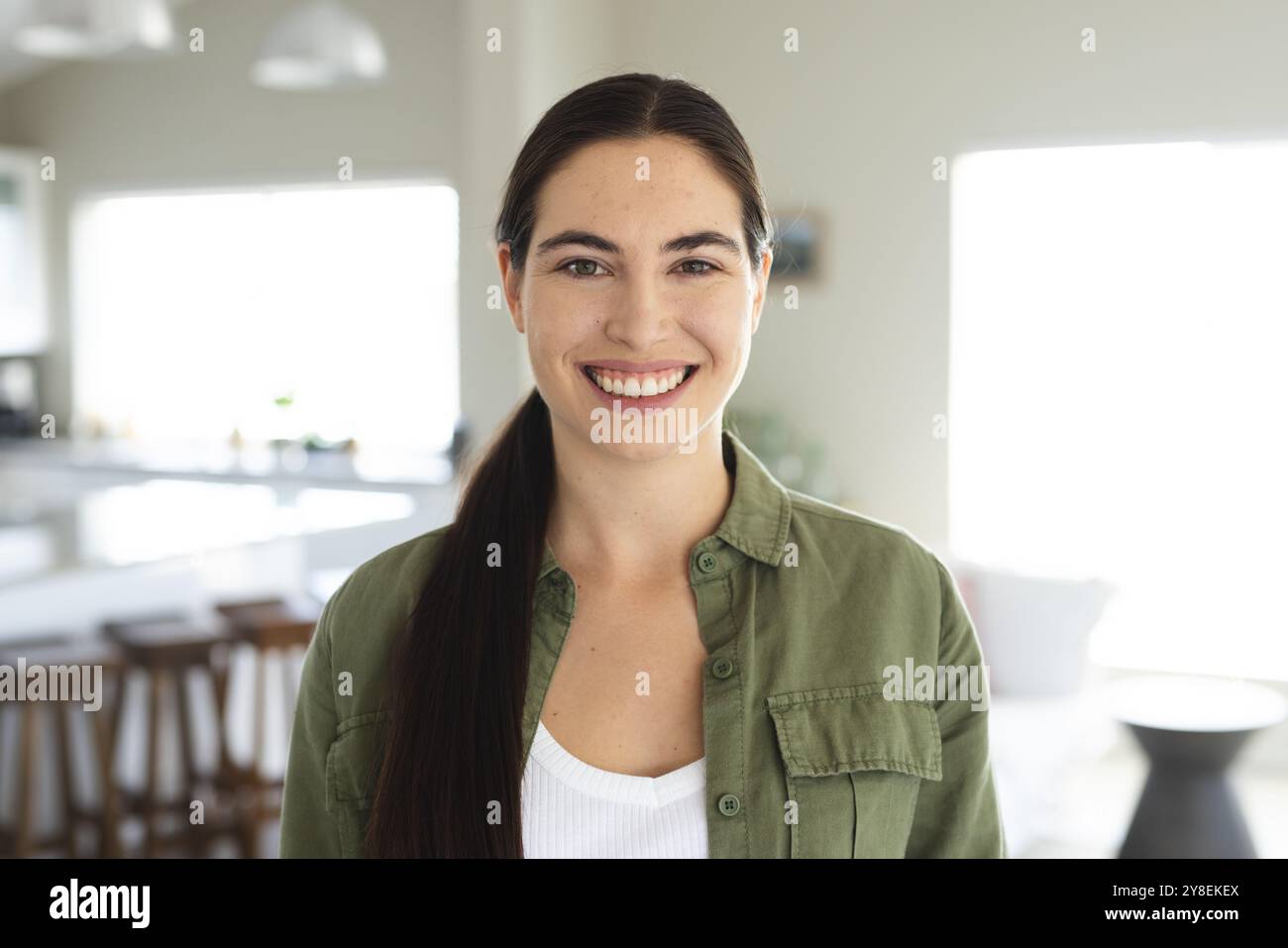 Portrait of smiling caucasian beautiful young woman dressed in jacket standing at home, copy space Stock Photo