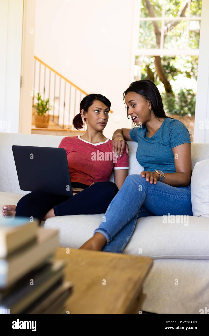 Happy biracial sisters sitting on couch and using laptop Stock Photo ...
