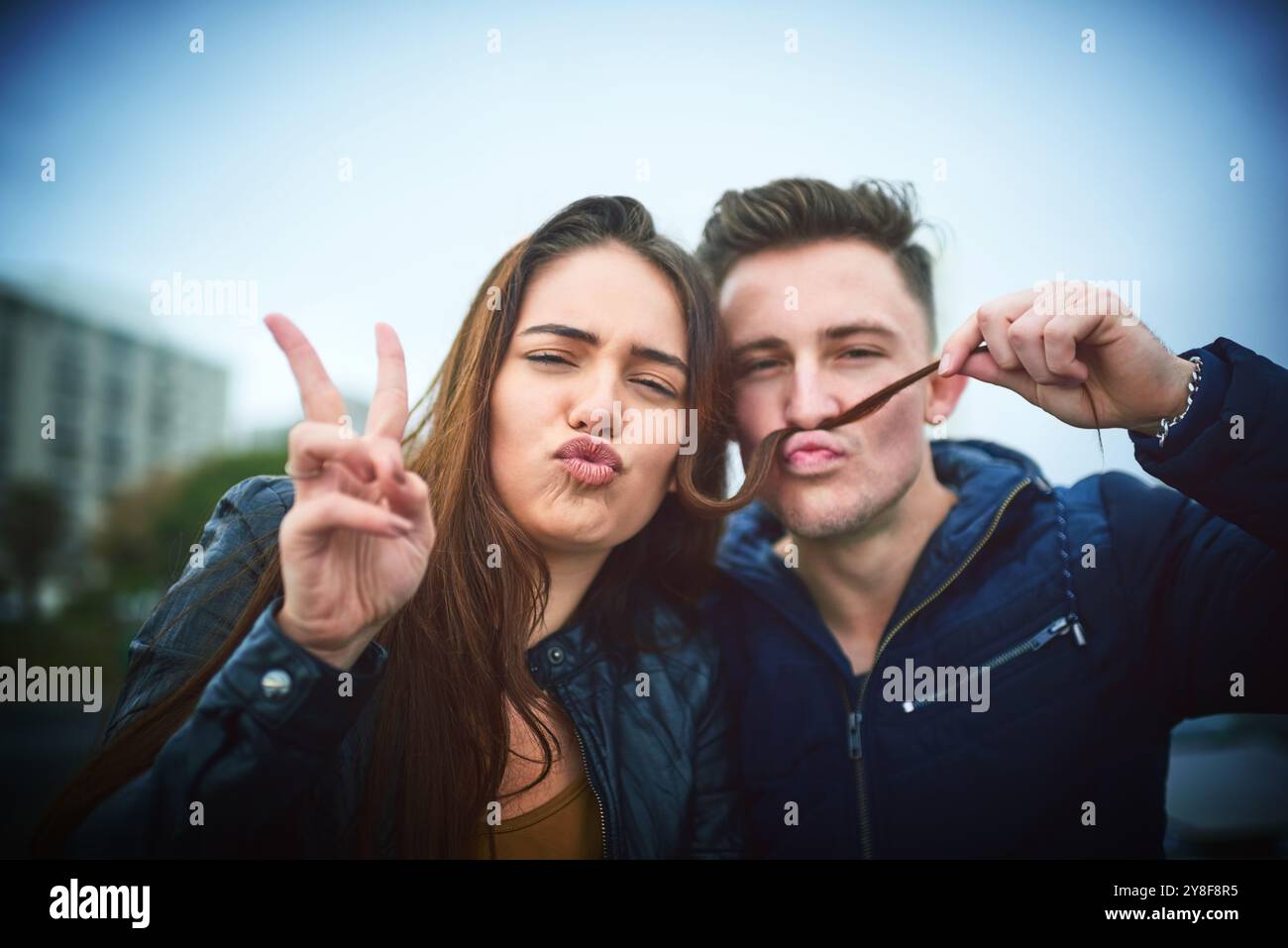 Portrait, playful and couple with peace sign outdoor for funny memory ...