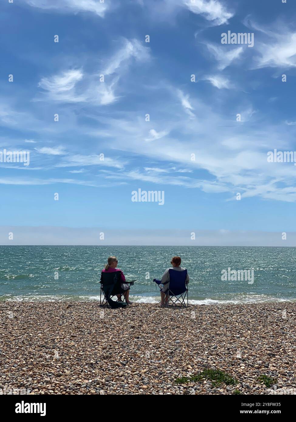 couple on shingle beach in deckchairs, Worthing, West Sussex, U.K. - Smartphone Captured Stock Image