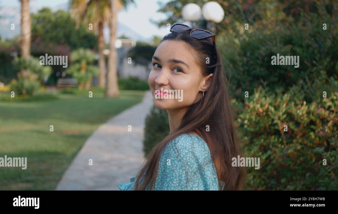 A woman with long hair is walking in a park Stock Photo