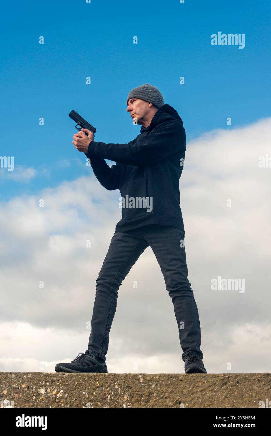 Man holding a gun outdoors, bookcover concept Stock Photo
