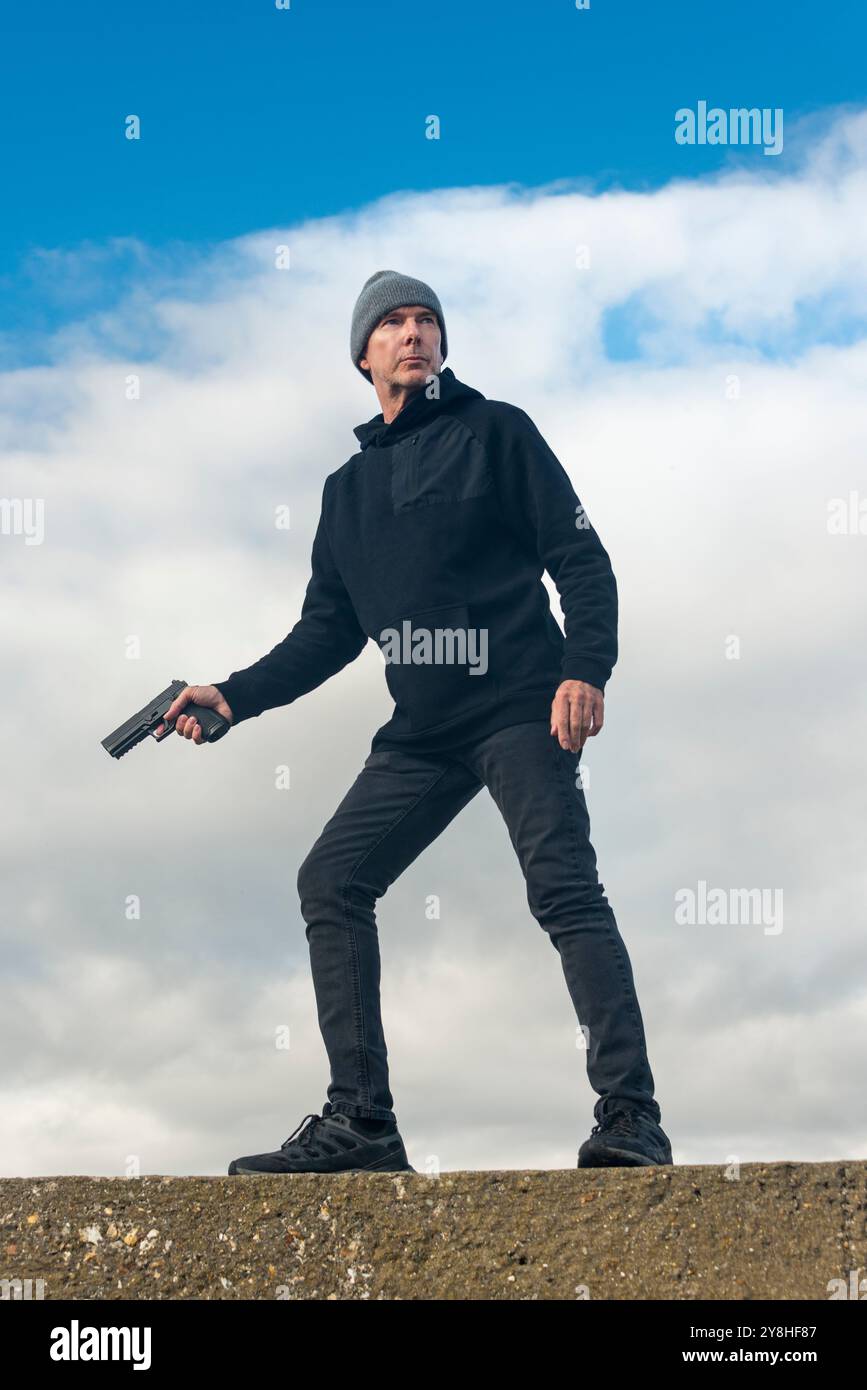 Man holding a gun outdoors, bookcover concept Stock Photo