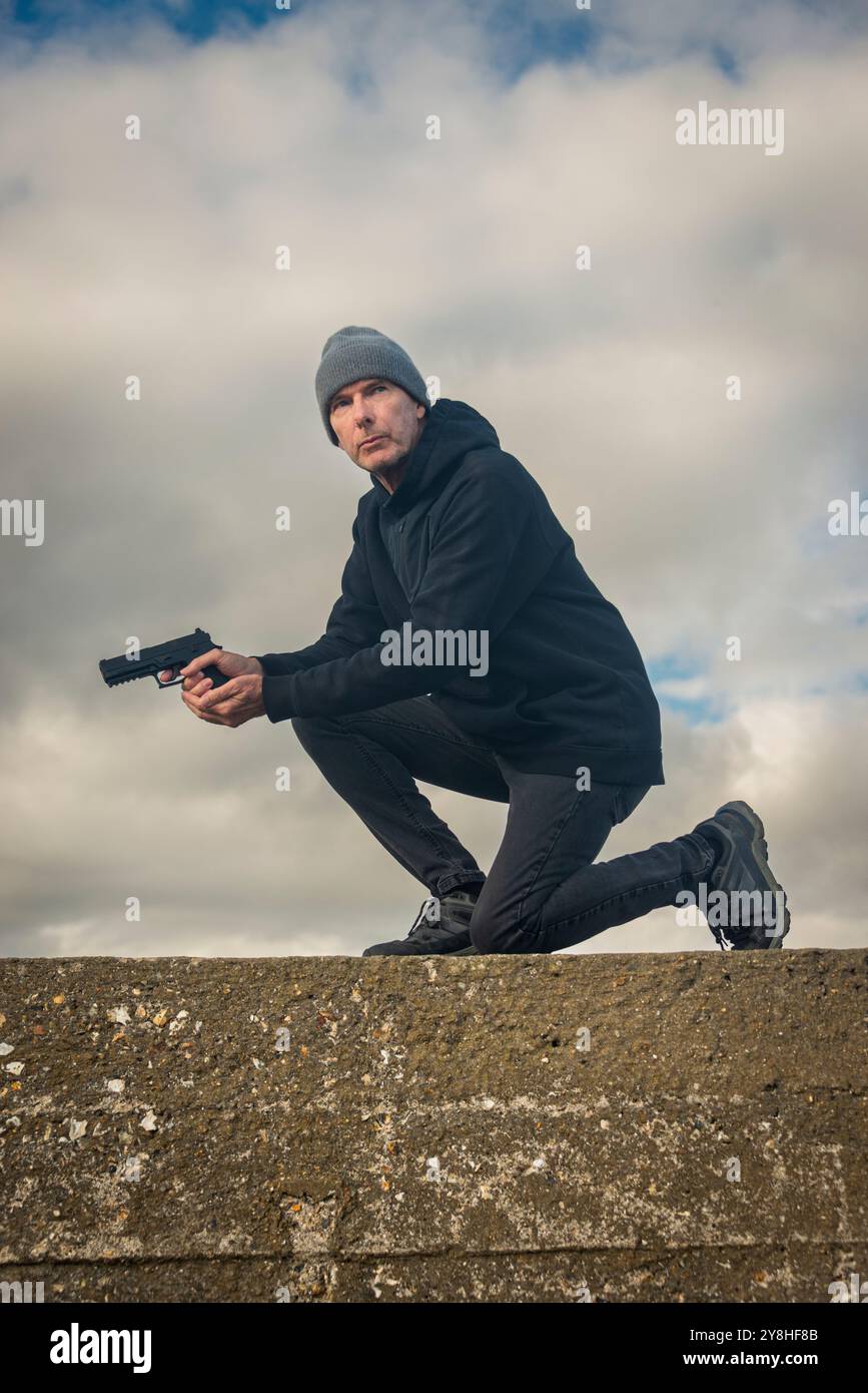 Man holding a gun outdoors, bookcover concept Stock Photo