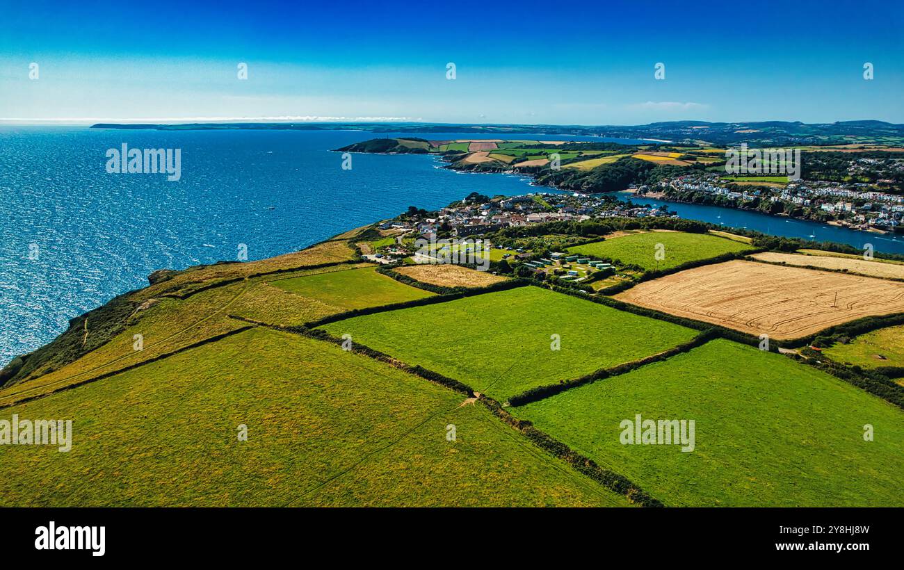 Aerial view of a coastal landscape featuring lush green fields, a small ...