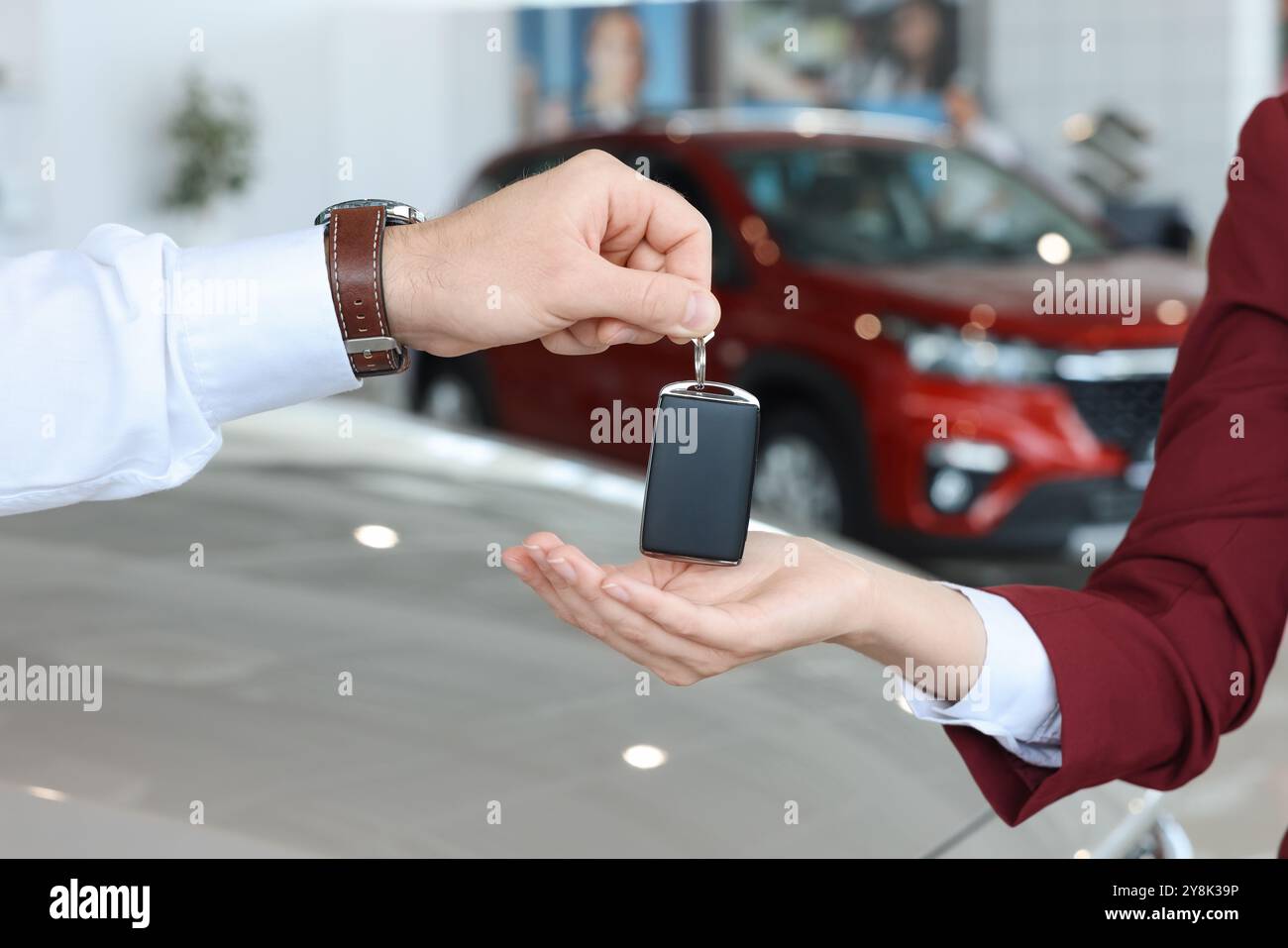 Salesman giving key to client near new car in salon, closeup Stock ...