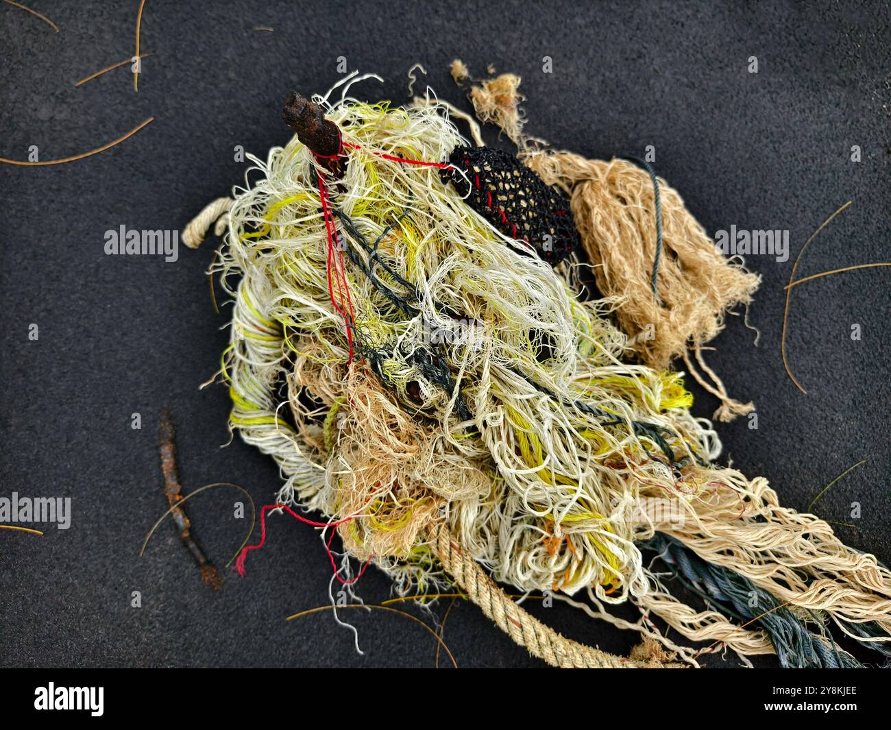 There is a pile of tightly wound rope and colorful yarn on a black ...