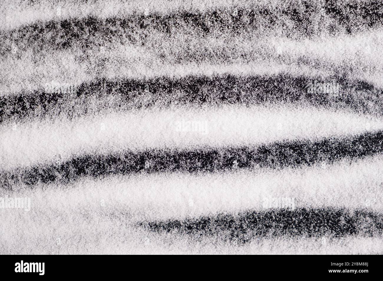 Finely ground stone white rock salt texture on black background, top view Stock Photo