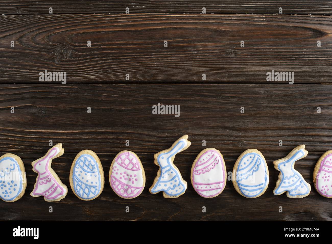 Easter frosted cookies in shape of egg, rabbit and chicken on wooden background. Flat lay with copy space Stock Photo