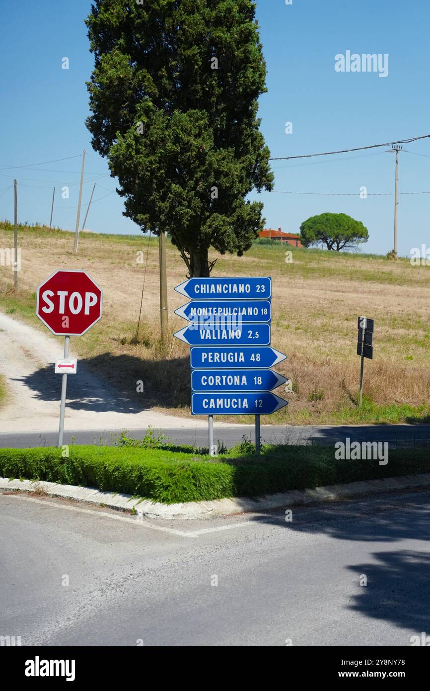 A classic blue road sign at a sun-drenched intersection in Tuscany ...