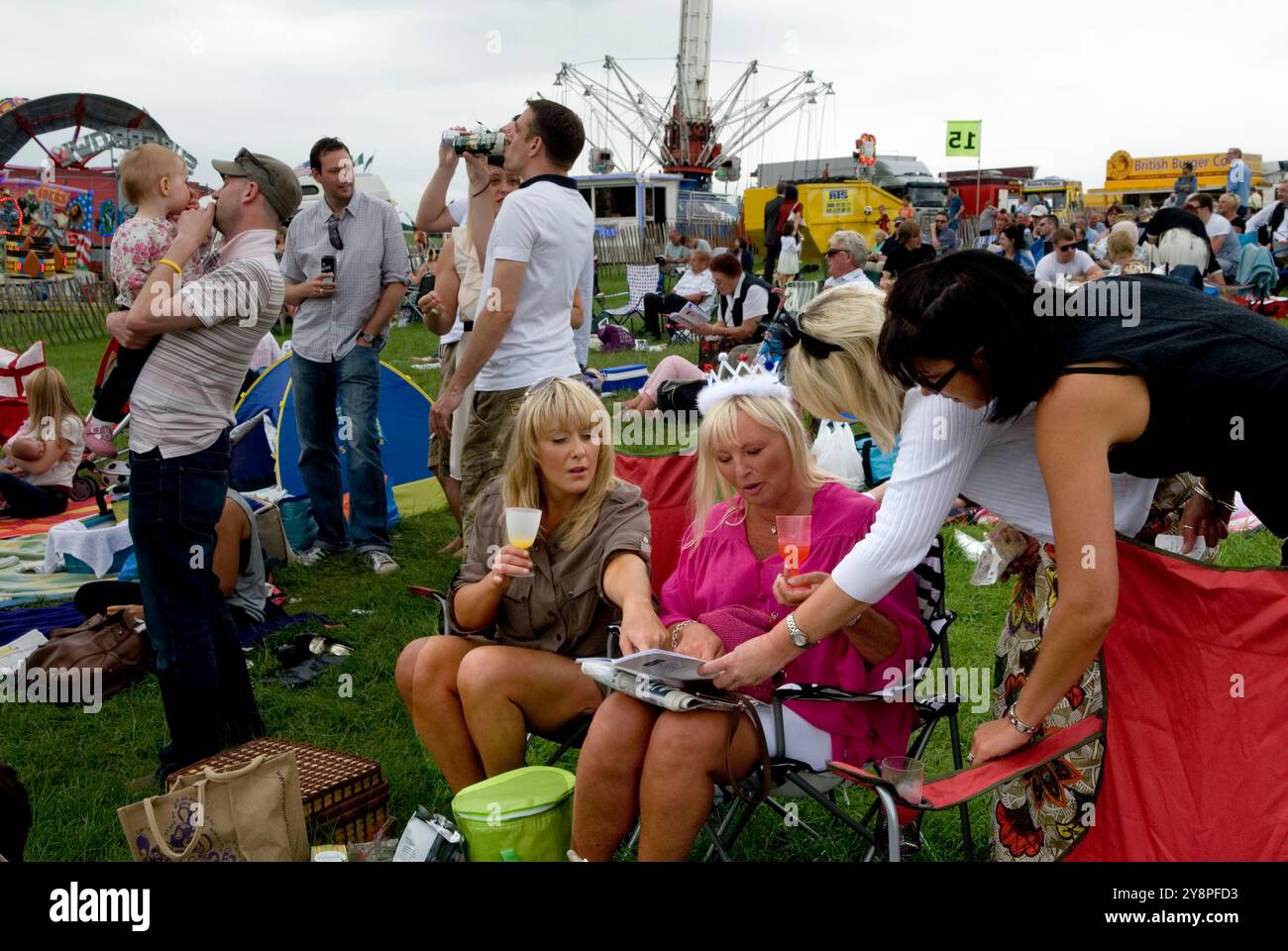Queen Elizabeths Diamond Jubilee, a group women, one wearing a pretend crowd celebrate at the Epsom Derby horse racing festival. Group local friends On the Hill ( the non paying side of the race track) Epsom Downs, Surrey, England 2012 2010s UK HOMER SYKES Stock Photo
