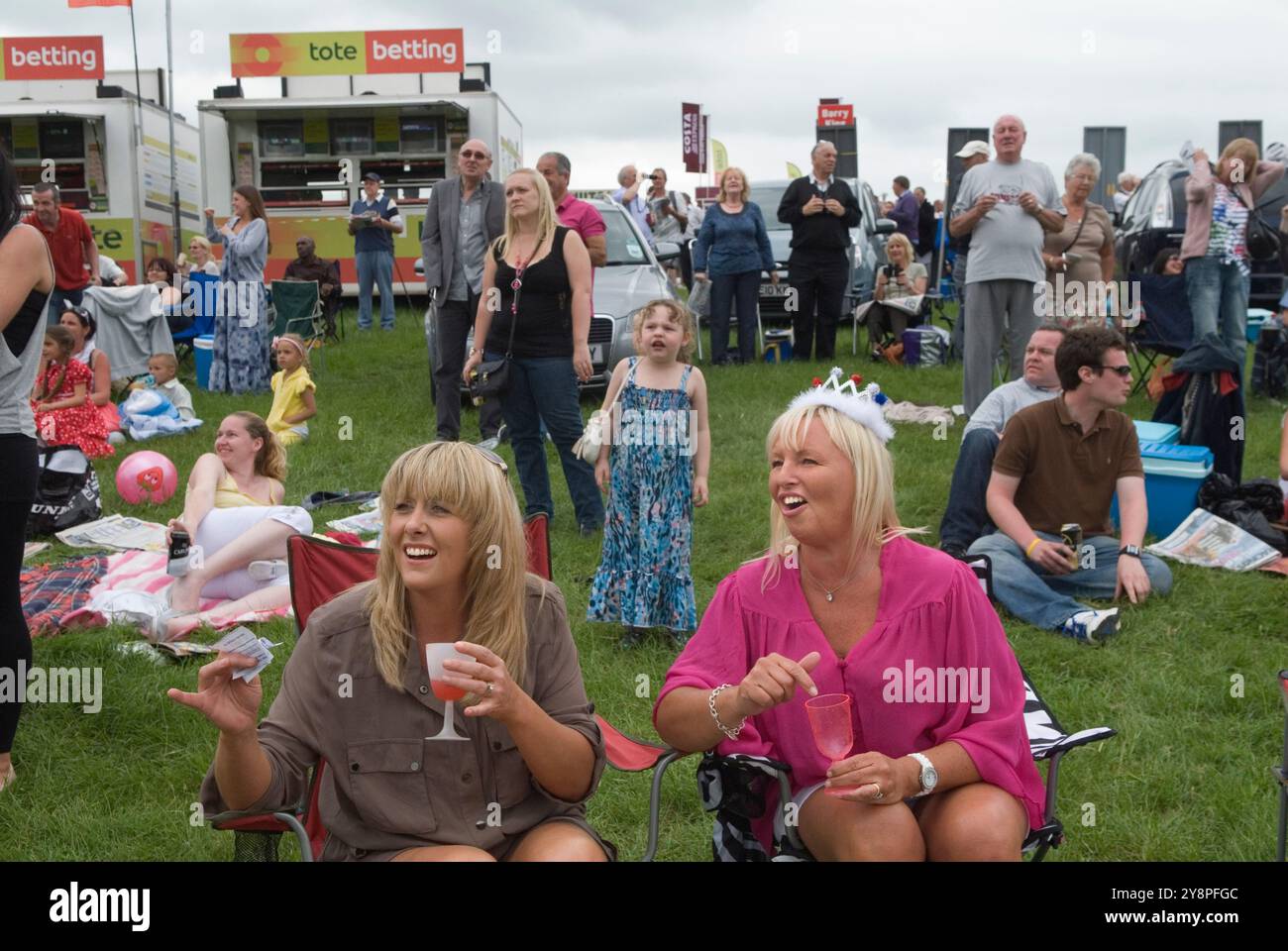 Queen Elizabeths Diamond Jubilee, a group women, one wearing a pretend crowd celebrate at the Epsom Derby horse racing festival. Group local friends On the Hill ( the non paying side of the race track) Epsom Downs, Surrey, England 2012 2010s UK HOMER SYKES Stock Photo