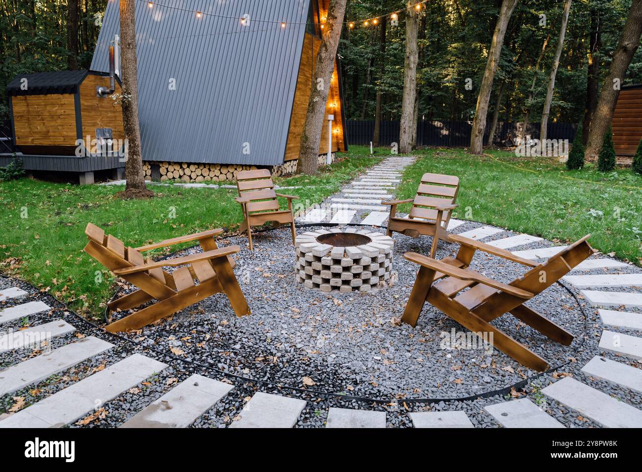 Outdoor seating area with wooden chairs around fire pit, surrounded by ...