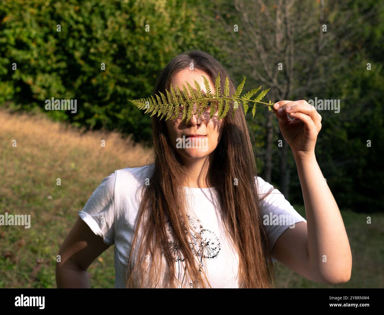 Portrait of a happy young woman with a fern leaf in her hand on ...