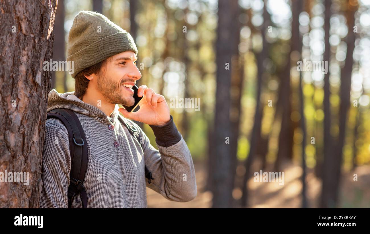 Happy young man backpacker talking on phone while hiking Stock Photo