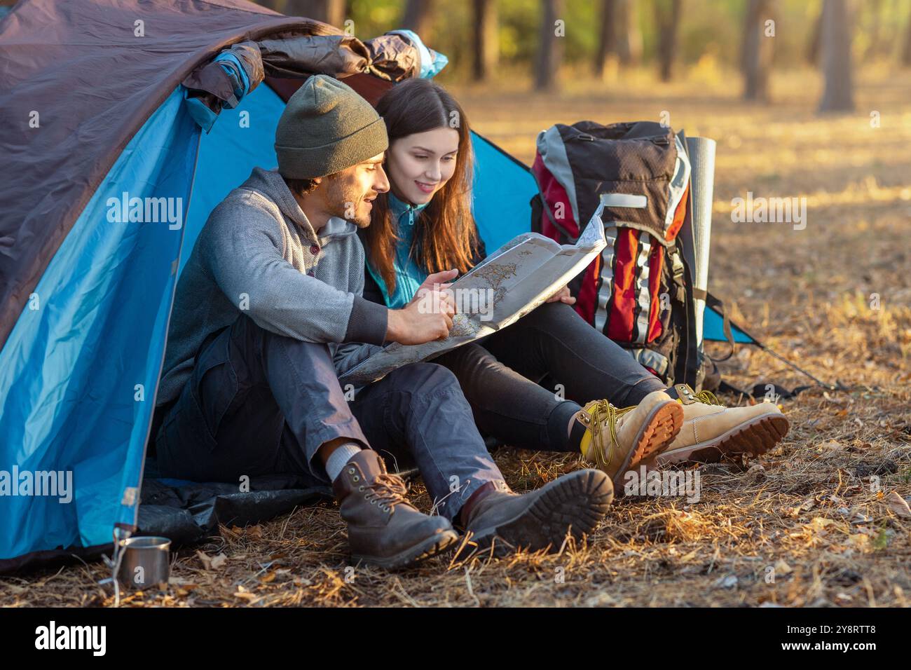 Romantic couple camping outdoors, sitting in tent and checking map ...