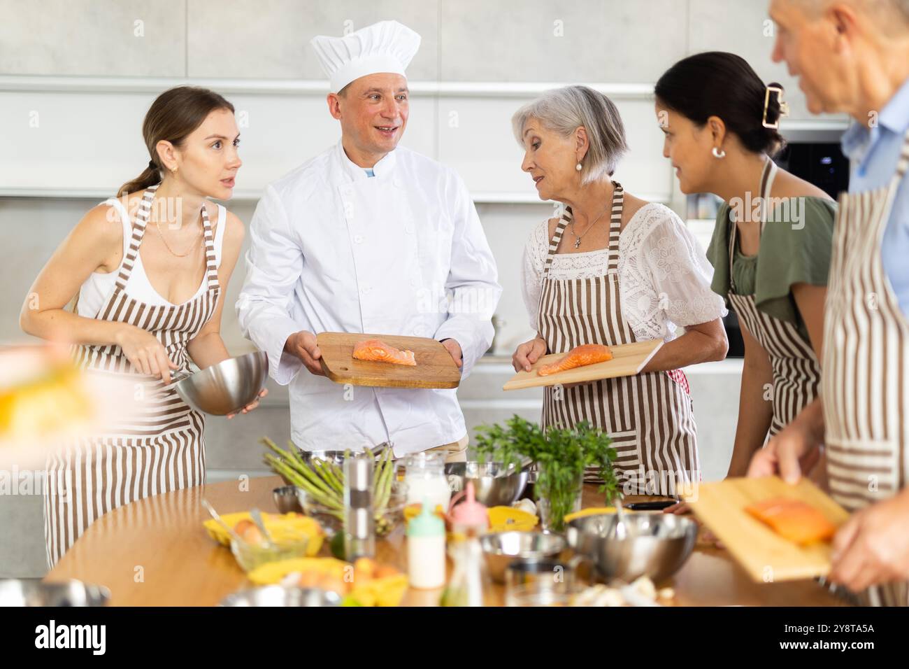 Chef in uniform teaches cooking class students how to clean and cut ...