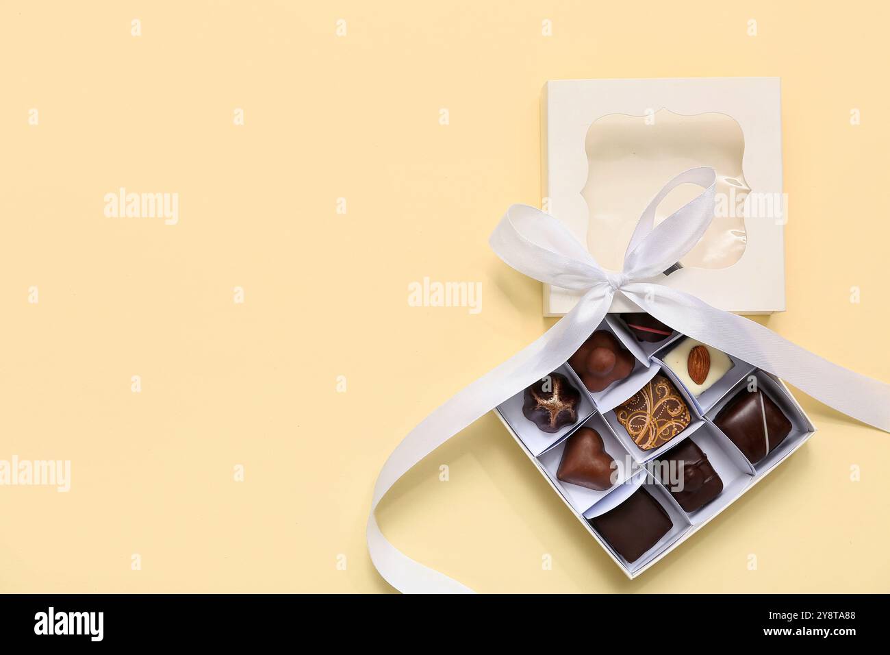 Box with tasty chocolate candies on yellow background Stock Photo - Alamy