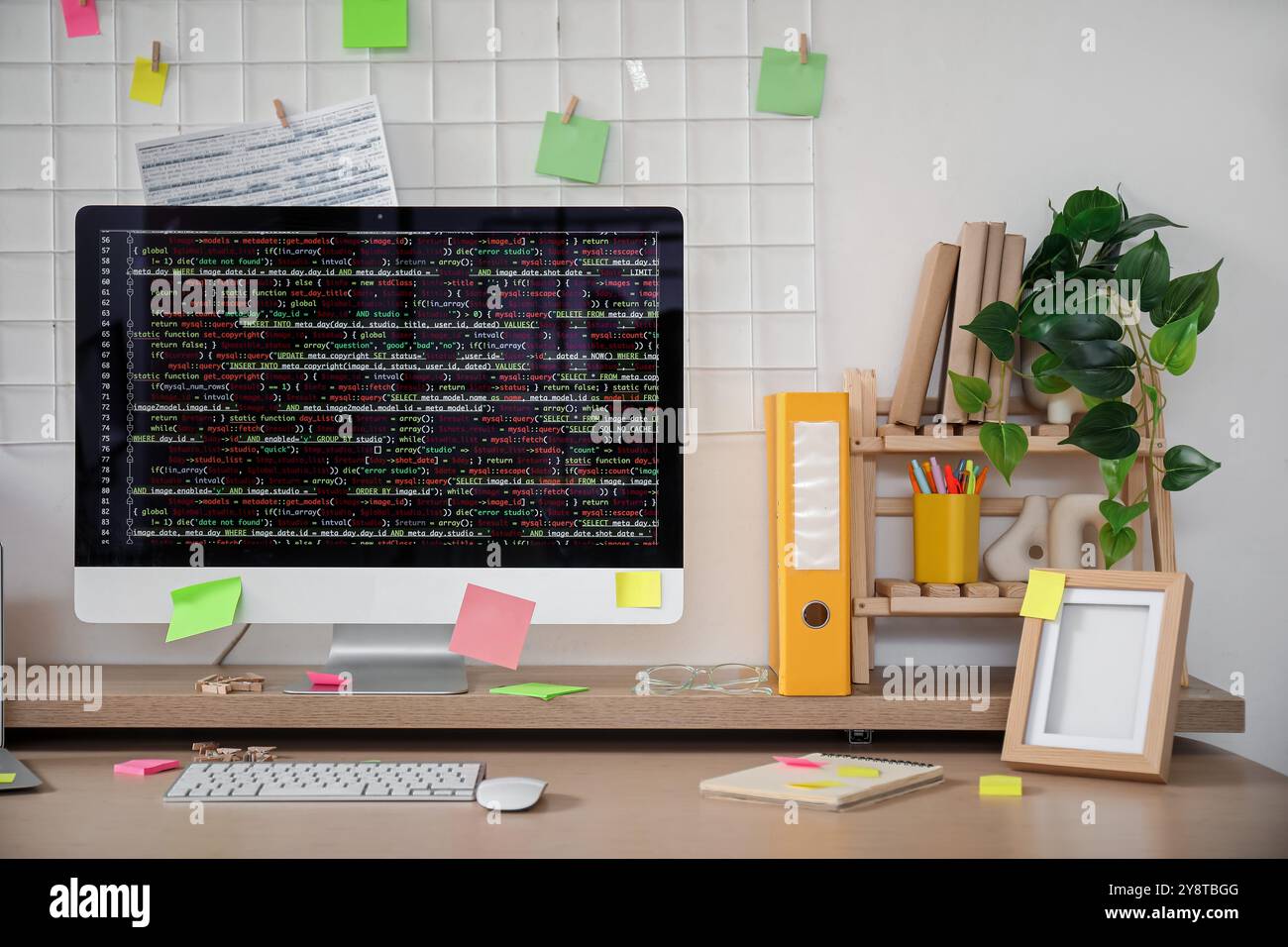 Computer monitor with code and sticky notes on programmer's desk in office Stock Photo