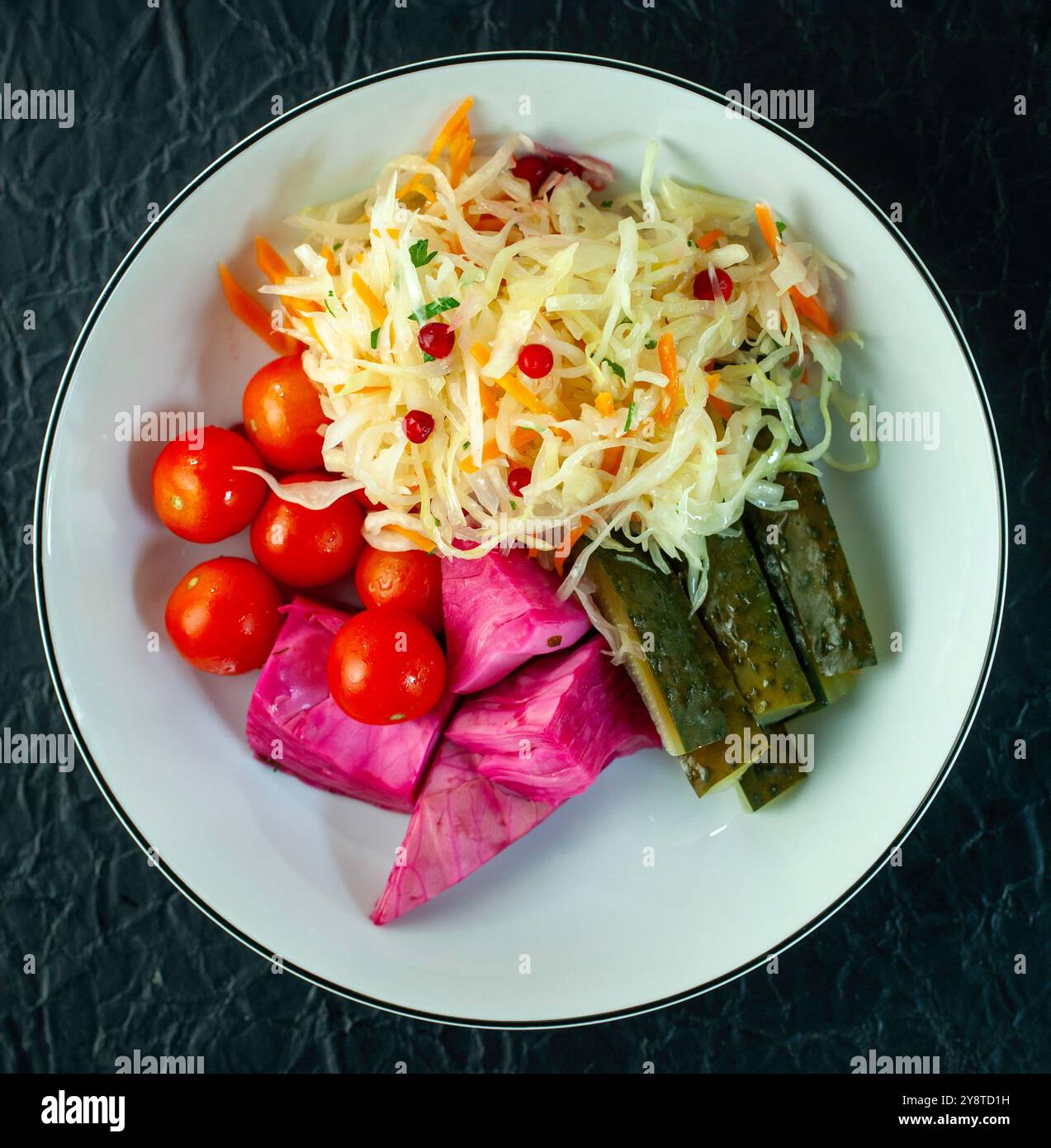 Plate combining sauerkraut, pickles and vegetables on dark background Stock Photo
