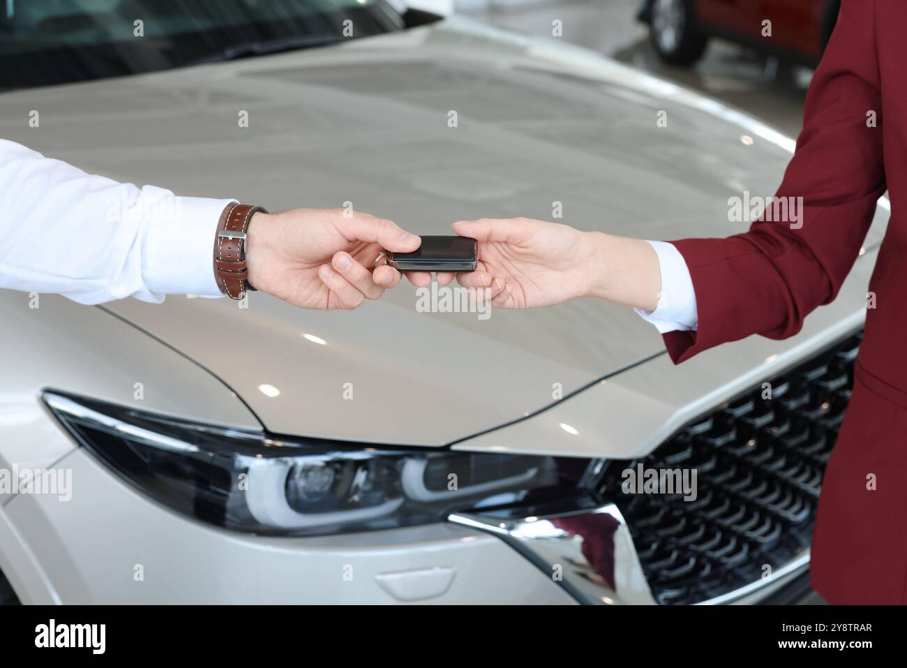 Salesman giving key to client near new car in salon, closeup Stock ...