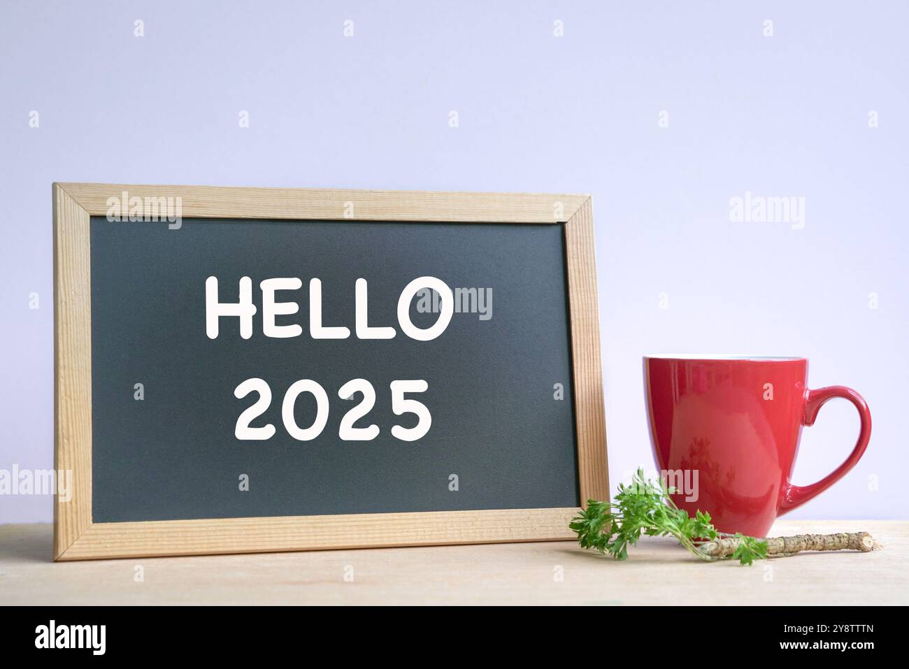 Hello 2025, text on a blackboard next to coffee in red cup. New year. Stock Photo