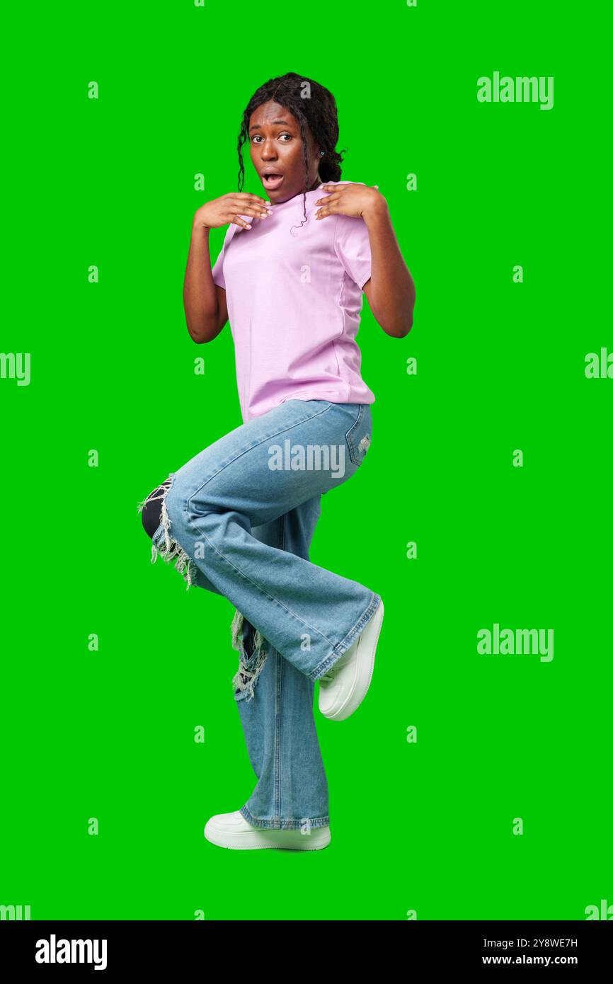 Surprised young woman against a vibrant green background expressing astonishment or shock Stock Photo