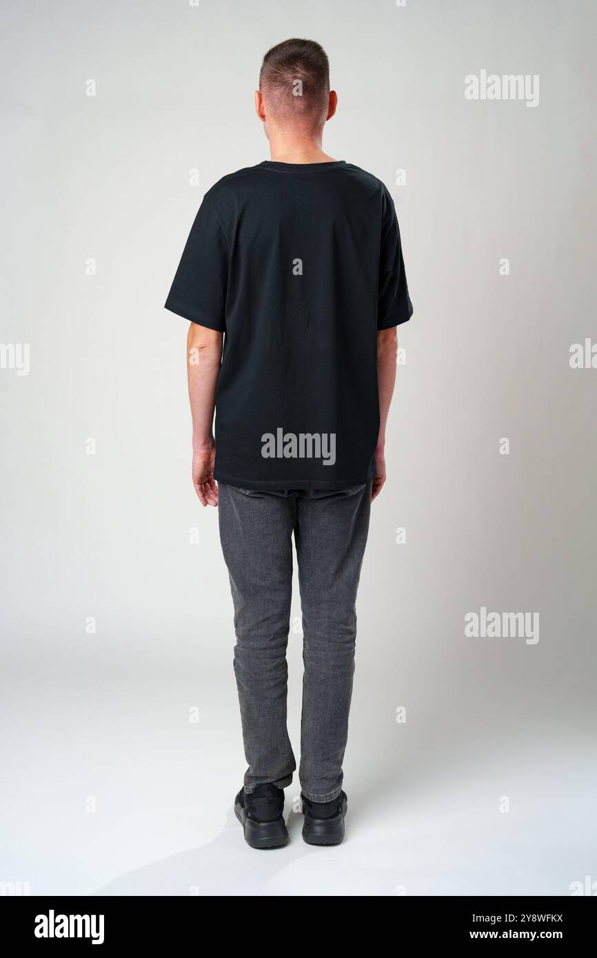 Back view of a casual man standing on gray backgorund in studio Stock Photo